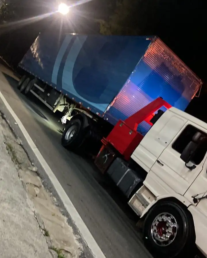 Carreta sendo rebocada à noite com sinalização